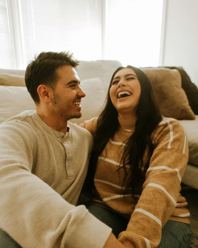 A couple laughing together on the sofa