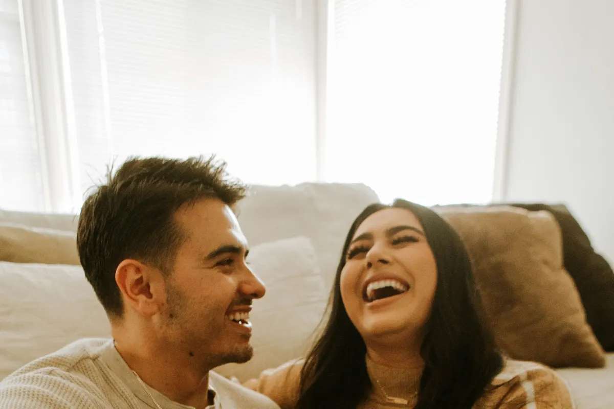 A couple laughing together on the sofa