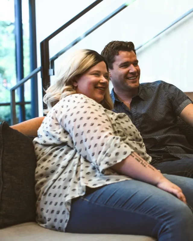 A couple smiling on the sofa, watching the screen